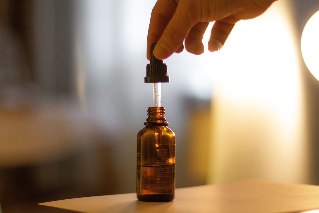 CBD oil in an amber dropper bottle on a wooden table with a blurry background.