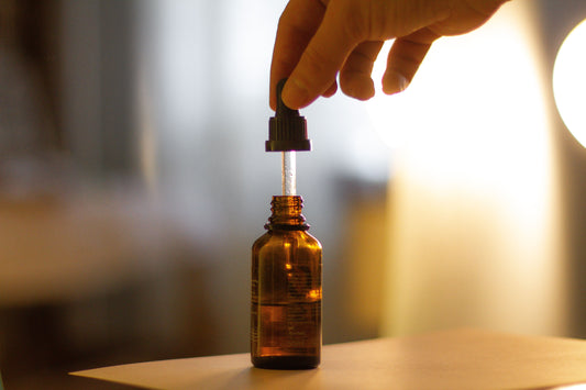 CBD oil in an amber dropper bottle on a wooden table with a blurry background.