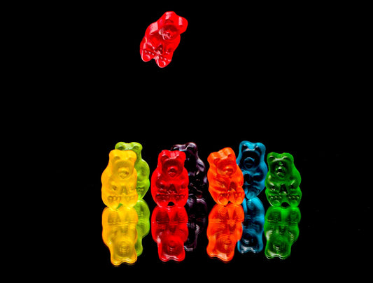 THC Gummies in various vibrant colours on a solid black background.