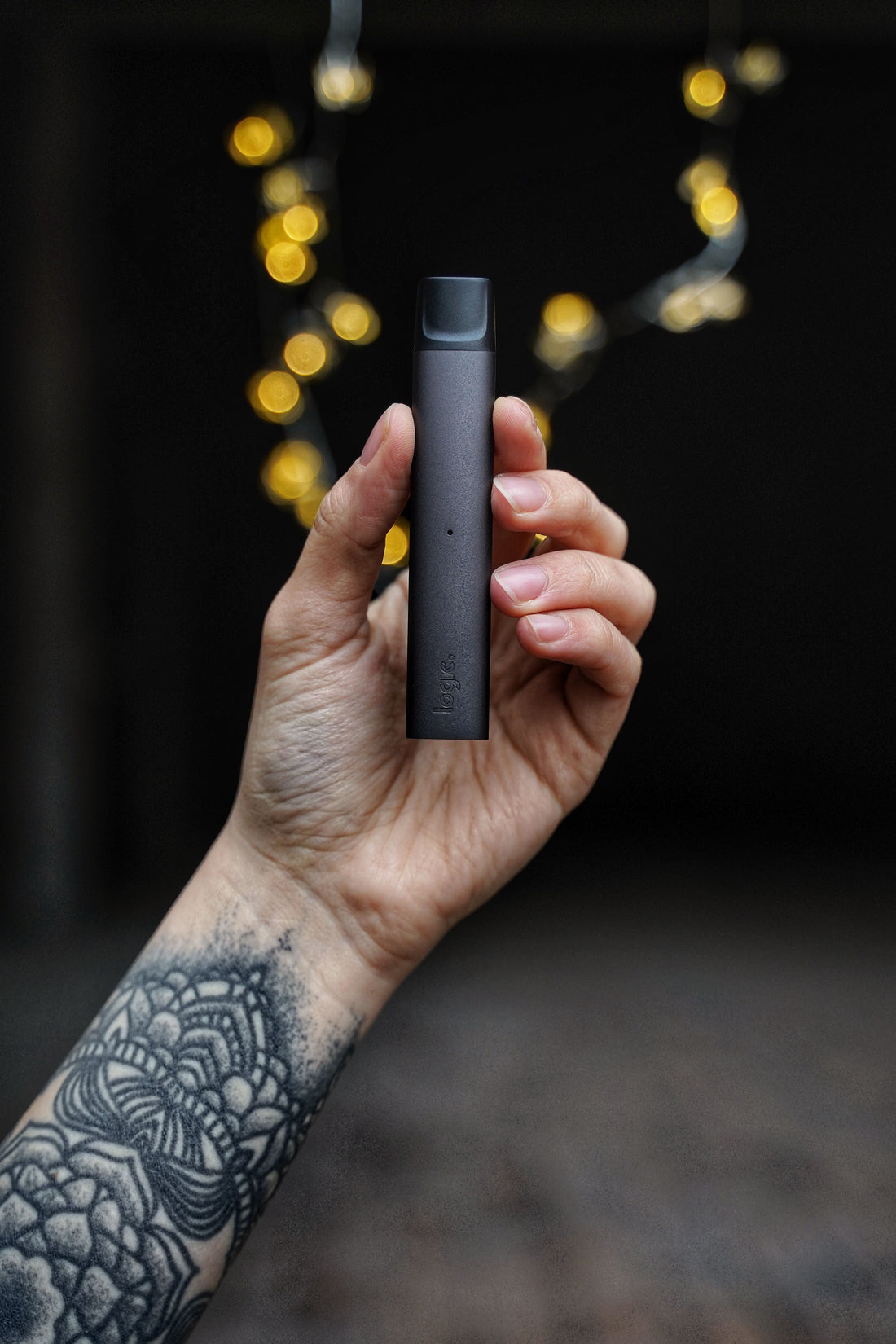 hand holding a thc vape with a dark background.