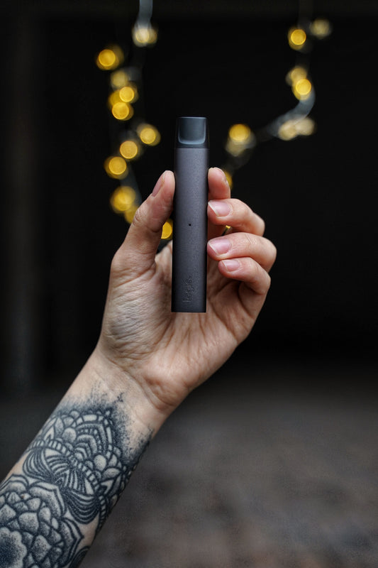 hand holding a thc vape with a dark background.