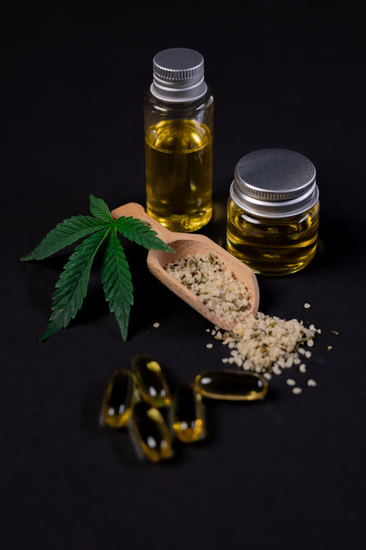 Hemp leaf, hemp seeds and hemp oil in glass jars on a dark background, alongside softgel capsules